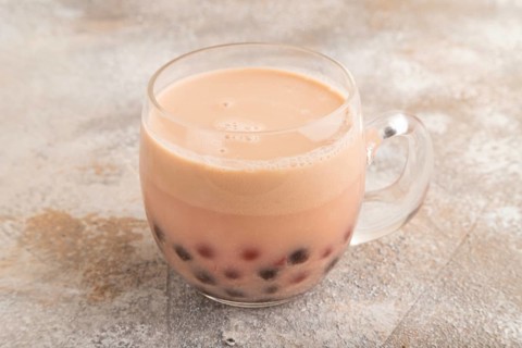 Bubble tea with pistachio and caramel in glass on brown concrete background. Healthy drink concept.