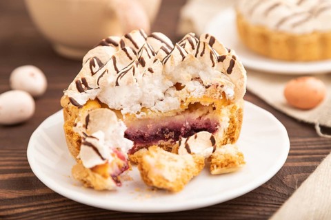 Tartlets with meringue cream and cup of coffee on brown wooden background and linen textile. side