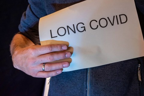 Man holding paper with Long Covid lettering in front of him, studio shot, Germany, Europe