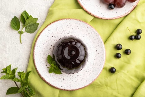 Black currant and grapes jelly on gray concrete background and green linen textile. top view, flat