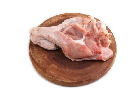 Raw turkey wing on a wooden cutting board isolated on white background. Side view, close up