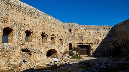 Walls of a historic fortress with arched windows under a clear sky, Chlemoutsi, High Medieval