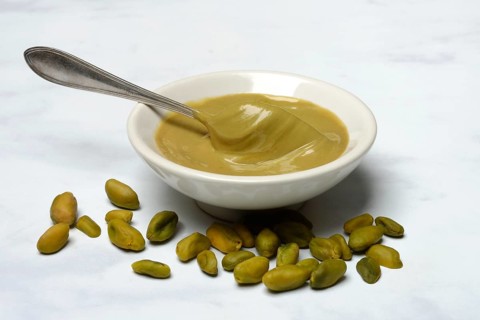 Pistachio cream in small bowls with spoon, pistachios