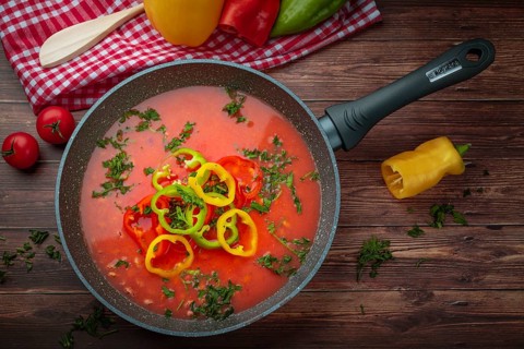 Bean soup with peppers in a pan, served with fresh herbs