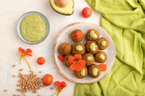Falafel with guacamole on white concrete background and green linen textile. Top view, flat lay,