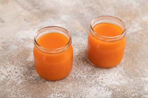 Baby puree with fruits mix, pumpkin, persimmon, mango infant formula in glass jar on brown concrete