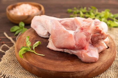 Raw turkey wing with herbs and spices on a wooden cutting board on a brown wooden background and