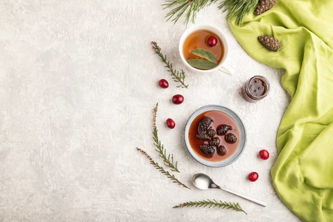 Pine cone jam with herbal tea on gray concrete background and green linen textile. Top view, flat
