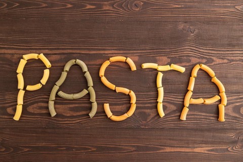 Inscription pasta, Rigatoni colored raw pasta with tomato, eggs, spices, herbs on brown wooden