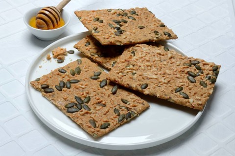 Crispbread with seeds and bowls of honey