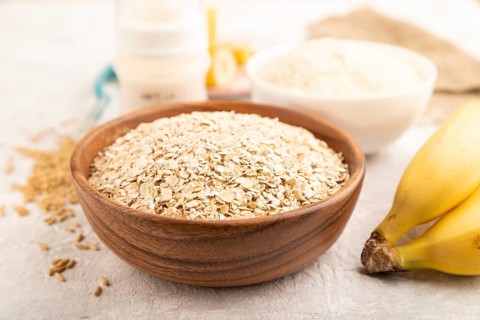 Powdered milk and oatmeal, banana baby food mix, infant formula, pacifier, bottle, spoon on gray