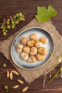 Grape (Burgundy) snails with butter and cheese on brown wooden background and linen textile. Top