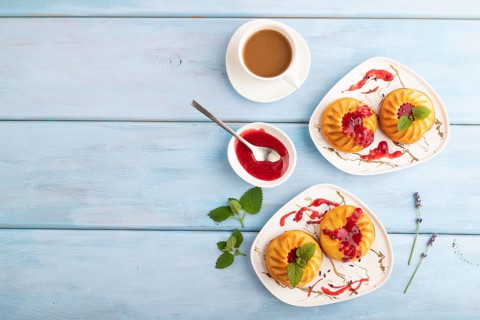 Semolina cheesecake with strawberry jam, lavender, cup of coffee on blue wooden background. top