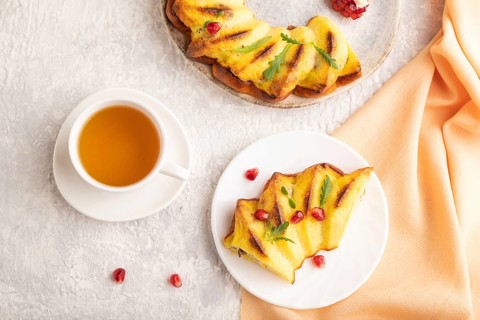 Cheesecake with cup of green tea on gray concrete background and orange linen textile. top view,