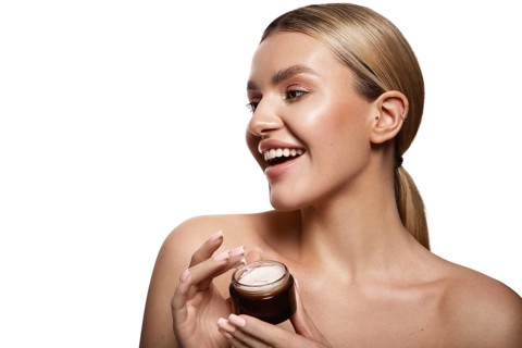 Beauty portrait of model with natural make-up holding a jar of cream. Fashion shiny highlighter on