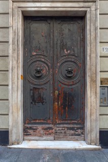 Two door knockers with lion heads on a large entrance door in the historic centre, Genoa, Italy,