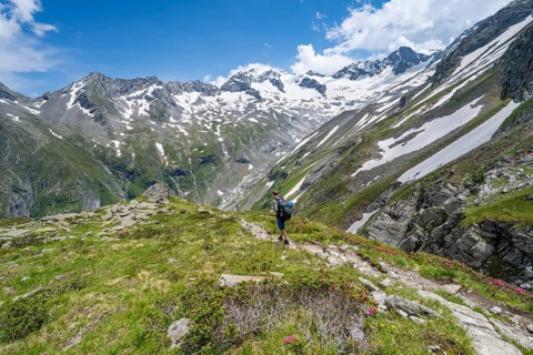 Mountaineer on hiking trail in picturesque mountain landscape, in the background mountain peak