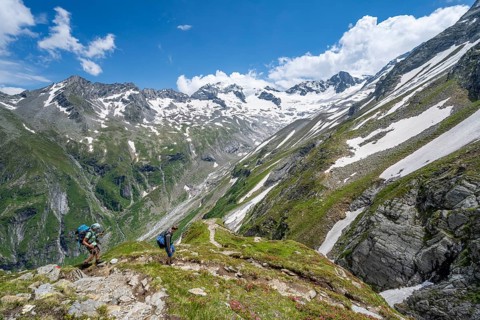 Mountaineer on hiking trail in picturesque mountain landscape, in the background mountain peak