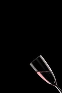 A champagne glass filled with rose sparkling wine against a black background