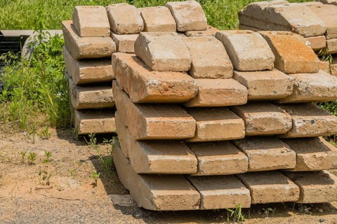 Curved concrete bricks used to support large utility poles stacked in rural countryside