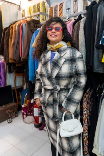 Vertical Portrait of a woman wearing jacket and sunglasses trying on clothes in a second hand store