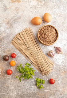 Japanese buckwheat soba noodles with tomato, eggs, spices, herbs on brown concrete background. Top