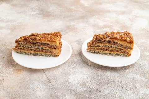 Walnut and hazelnut cake with caramel cream on brown concrete background. side view