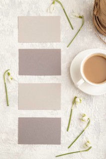 Gray paper business card mockup with spring snowdrop galanthus flowers and cup of coffee on gray