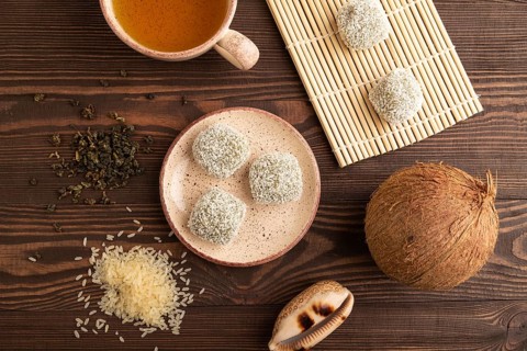 Japanese rice sweet buns mochi filled with pandan and coconut jam and cup of green tea on brown
