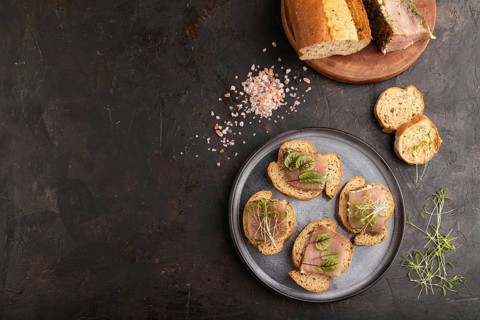 Bread sandwiches with jerky salted meat, sorrel and cilantro microgreen on black concrete