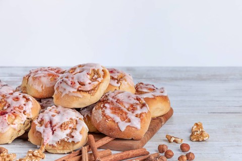 Delicious cinnamon biscuits with nuts and icing on a wooden base
