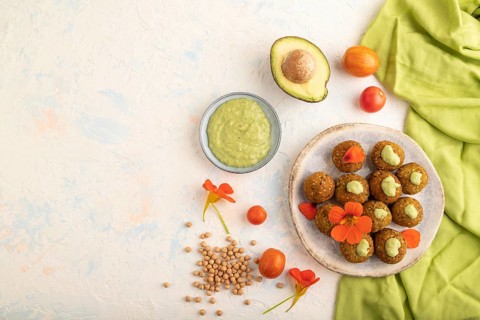 Falafel with guacamole on white concrete background and green linen textile. Top view, flat lay,