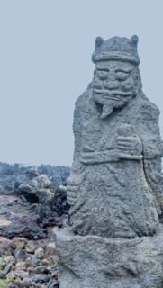 Ancient stone carved figure of sea god on coast of Jeju island, South Korea, Asia