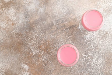 Sweet strawberry liqueur in glass on a gray concrete background. top view, copy space, flat lay