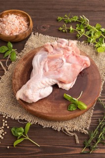 Raw turkey wing with herbs and spices on a wooden cutting board on a brown wooden background and
