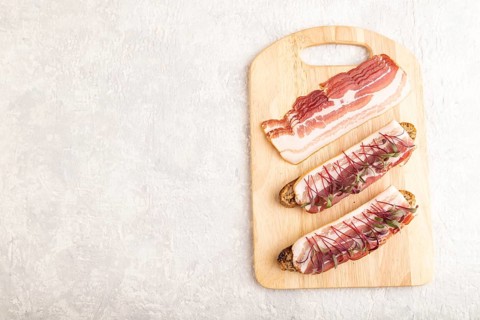 Bread sandwiches with jerky salted meat and lard with beet microgreen on gray concrete background.