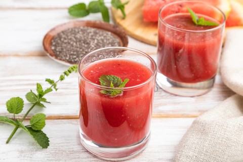 Watermelon juice with chia seeds and mint in glass on a white wooden background with linen textile.