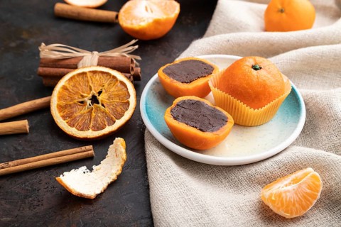 Truffle chocolate tangerine candies on a black concrete background and linen textile. Side view,
