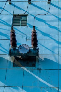 High voltage power lines with ceramic insulators on side of power transfer station building