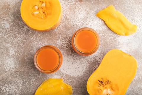 Baby puree with fruits mix, pumpkin, persimmon, mango infant formula in glass jar on brown concrete