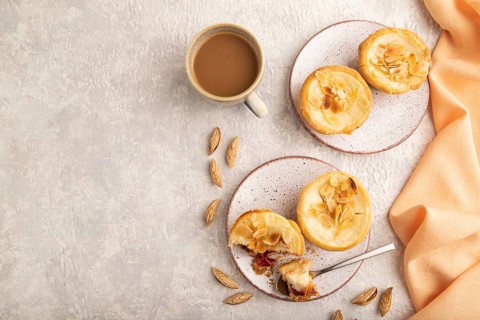 Traditional portuguese cakes pasteis de nata, custard small pies with almonds with cup of coffee on