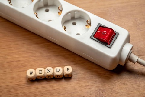 Concept image energy turnaround, switchable socket strip on wooden floor, letter cubes form the