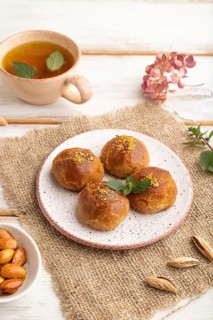 Homemade traditional turkish dessert sekerpare with almonds and honey, cup of green tea on white