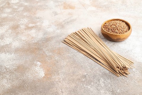 Japanese buckwheat soba noodles with tomato, eggs, spices, herbs on brown concrete background. Side