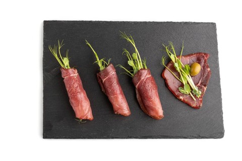 Slices of smoked salted meat with green pea microgreen isolated on white background. Top view, flat