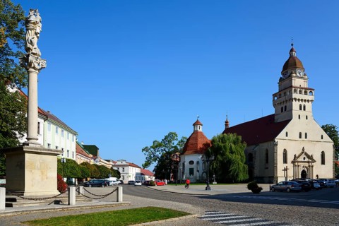 Town square with a statue in the foreground, church in the background on a sunny day, Roman
