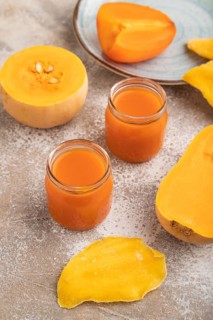Baby puree with fruits mix, pumpkin, persimmon, mango infant formula in glass jar on brown concrete