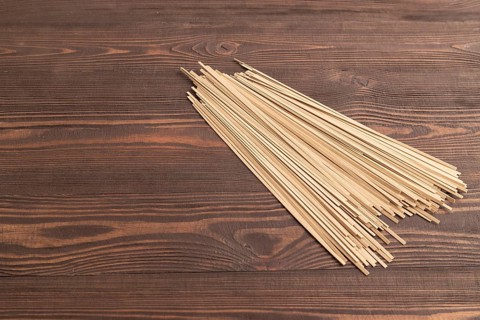 Japanese buckwheat soba noodles on brown wooden background. Side view, copy space