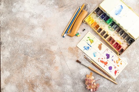 Drawing accessories set: brushes, pencils, watercolor on brown concrete background. Top view, flat