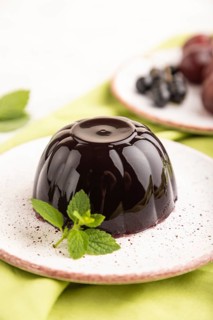 Black currant and grapes jelly on gray concrete background and green linen textile. side view,